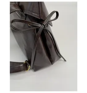Detail shot of vintage leather backpack side featuring a bow and gold metal buckle