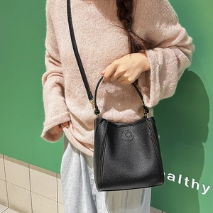 Close-up of black lychee grain leather bucket bag with embossed logo and shoulder strap