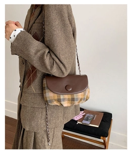 Detail view of a vintage saddle bag with brown leather flap and checkered fabric texture