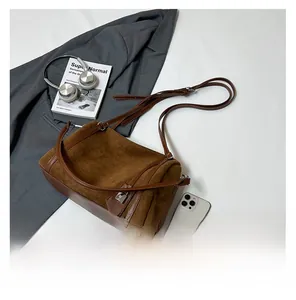 Detailed view of a brown suede Boston tote bag styled with lifestyle accessories and smartphone