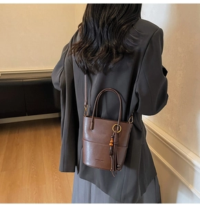 Detail of vintage brown leather bucket bag with tassel and wooden bead charm accessory