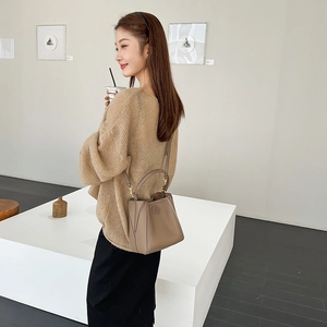 Brown leather trapezoid bucket bag with logo embossing and cylindrical top handle