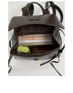 Top view of open dark brown leather backpack showing internal storage space with pocket