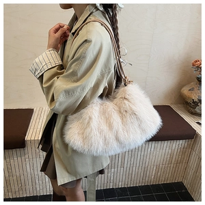 Close-up of beige plush faux fur shoulder bag with slender straps worn by a model