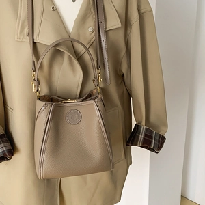 Detail of clay brown bucket bag showing lychee grain leather and gold metal lock