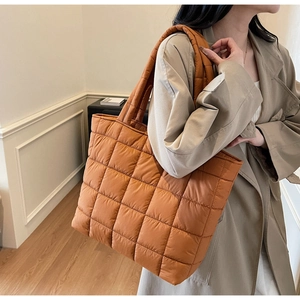 Close-up of a large caramel quilted tote bag featuring a classic lattice stitch pattern