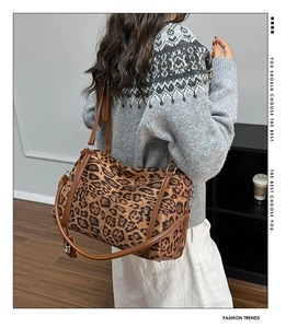 Detail of leopard print tote bag with brown leather handles and silver hardware accents