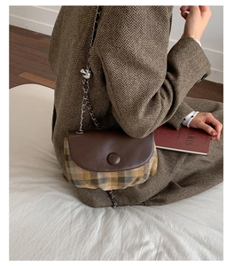 Retro plaid saddle bag with brown leather flap and chain strap in casual setting