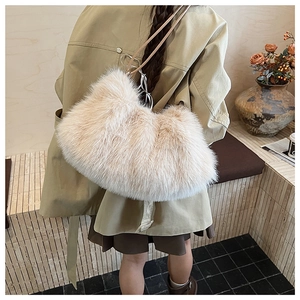 Detail of soft cream faux fur hobo bag with brown leather strap worn by a model