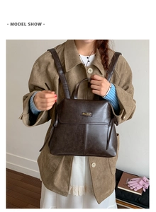 Detail view of a vintage dark brown leather backpack with a classic metal logo plate