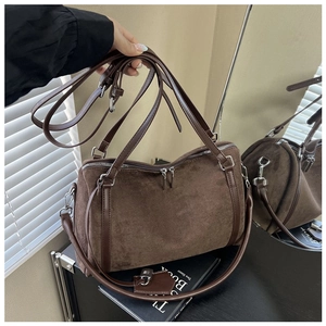 Detail of dark brown suede tote bag with leather straps and silver hardware in soft light