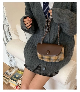 Retro saddle bag with brown plaid fabric and leather flap shown on a seated model
