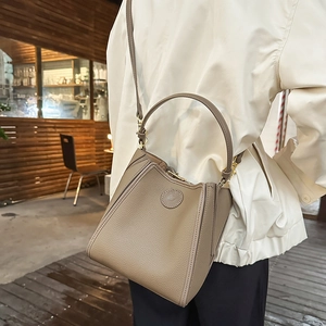 Detail of a brown lychee pattern leather bucket bag with golden hardware and logo