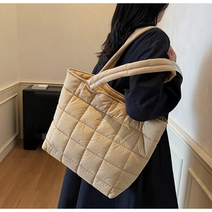 Detailed view of beige quilted tote bag showing wide straps and soft nylon texture