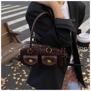 Detail of vintage oil-wax leather shoulder bag with gold hardware in autumn street scene