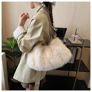 Detail of plush faux fur shoulder bag in beige with slim leather strap for autumn