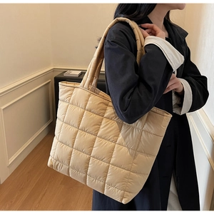 Close-up detail of beige quilted tote bag showing large square stitching and soft texture