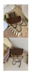 Detail of wool plaid saddle bag with chain strap and 100% wool tag in cozy setting