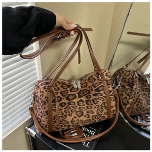 Detail of leopard print cylinder bag with leather handles and metallic zipper hardware