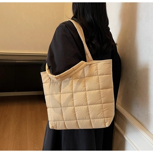 Quilted beige tote bag detail showing the soft padded texture and wide shoulder strap
