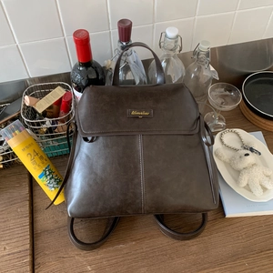 Detailed view of coffee brown faux leather backpack with Aimaior logo on a wooden table