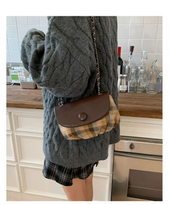 Brown checkered crossbody saddle bag with chain strap and leather flap shown on model