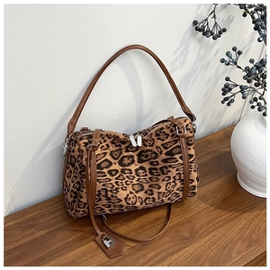 Close-up of leopard print tote bag with brown leather straps on a wooden table