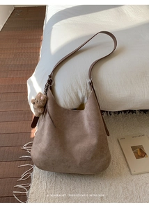 Detail of retro tan hobo bag in suede texture with a cute teddy bear plush charm