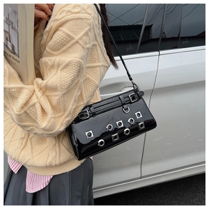Close-up of black patent leather underarm bag with silver metal eyelets and studs