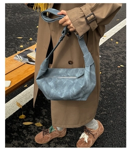Outdoor shot of a vintage blue-grey dumpling bag worn by a model in autumn streets