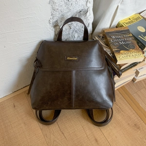Detailed view of vintage dark brown faux leather backpack with metallic logo plaque