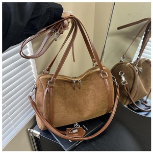 Detailed macro view of brown suede tote bag featuring leather handles and silver hardware
