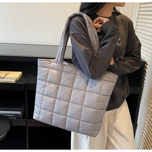 Detailed view of light gray quilted tote bag with square pattern showing on model