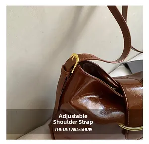Détail de la bandoulière réglable sur le cabas vintage en cuir marron avec boucle dorée