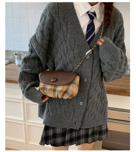 Detail of vintage saddle bag featuring brown leather flap and checkered fabric with chain strap