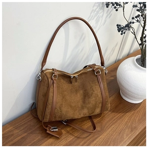 Close-up of brown suede tote bag on wooden surface with silver metallic hardware