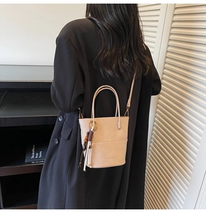 Detail of apricot bucket bag with tassel pendant on black blazer outfit