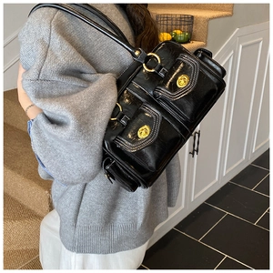 Detail of black oil wax leather shoulder bag with gold locks and white stitching