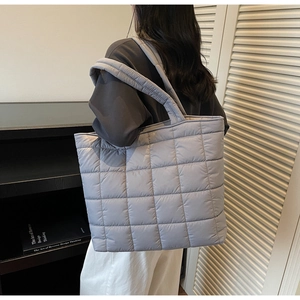 Detail of light blue quilted tote bag with padded texture and stitched grid pattern
