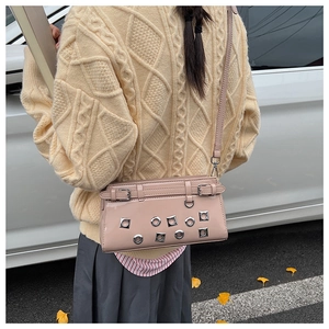 Pink patent leather crossbody bag with silver eyelets shown on a model's back detail