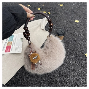 Detail of fuzzy faux fur tote bag with wooden bead handle and a small teddy bear charm