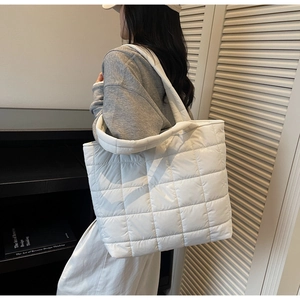 Detail of white quilted puffer tote bag showing large capacity and soft padded texture
