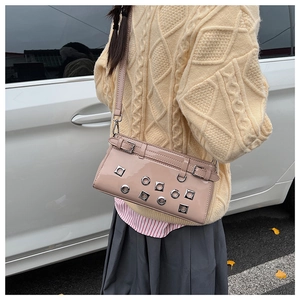 Close-up of pink crossbody bag featuring metal rivets and hollow-out detailing on leather