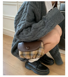 Detail of vintage saddle bag with brown faux leather flap and plaid fabric body