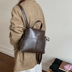 Detail of vintage brown leather backpack with drawstring and flap closure on model
