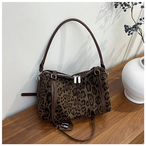 Detailed view of leopard print tote bag with brown leather handles on a wooden table