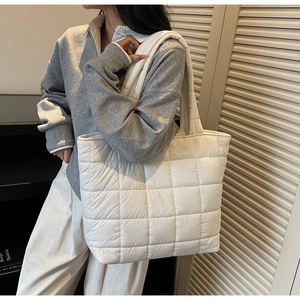 Detail of white quilted tote bag featuring classic grid pattern and thick padded straps
