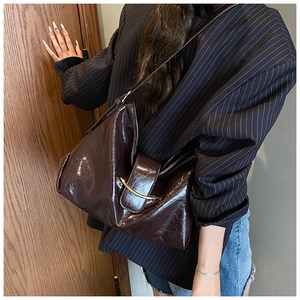 Détail du sac à bandoulière en cuir ciré marron avec boucle dorée en demi-lune