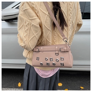 Close-up of pink patent leather shoulder bag with silver grommets and buckle details