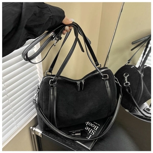 Detail view of black faux suede Boston tote bag with glossy leather handles and dual zippers
